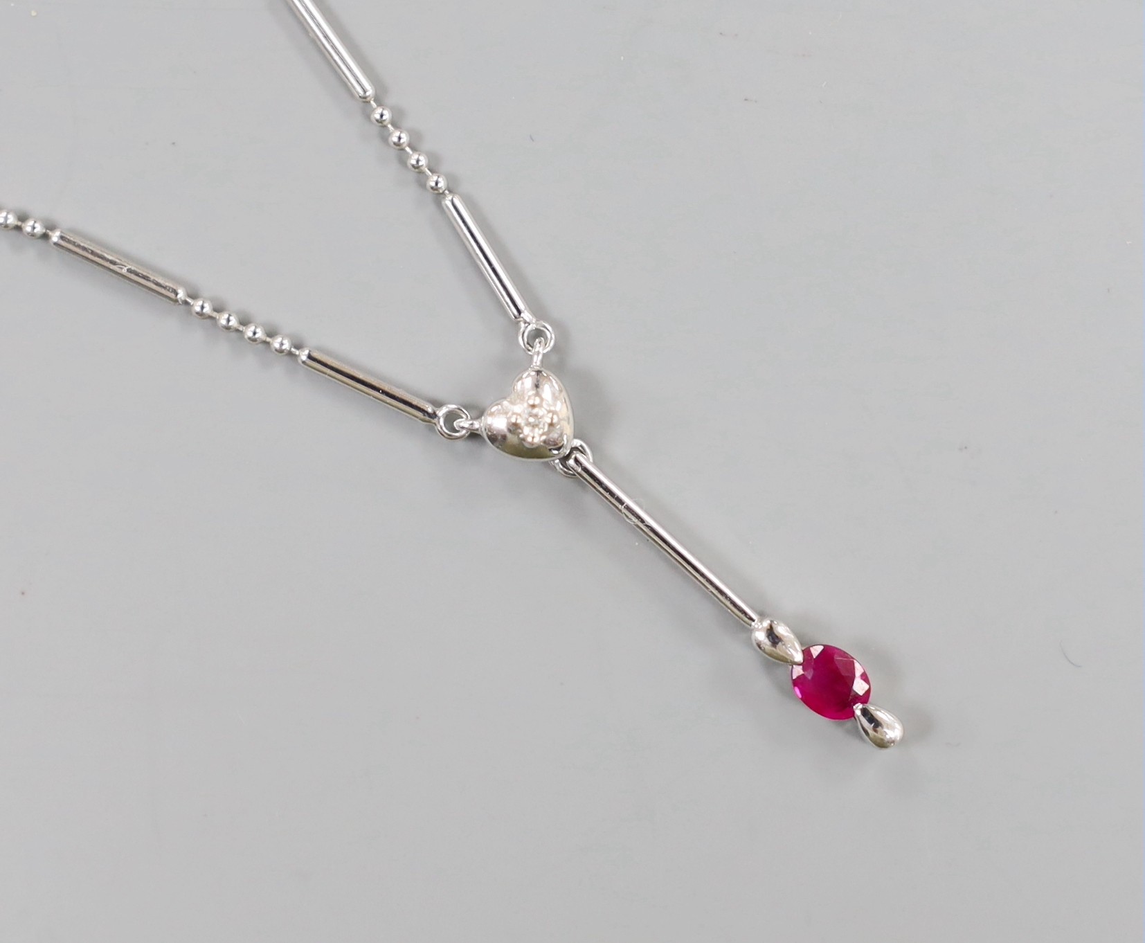 An 18ct white gold (750) pendant with ruby drop on bar and long link chain with silver clasp, chain 38cm, gross 4.8 grams.